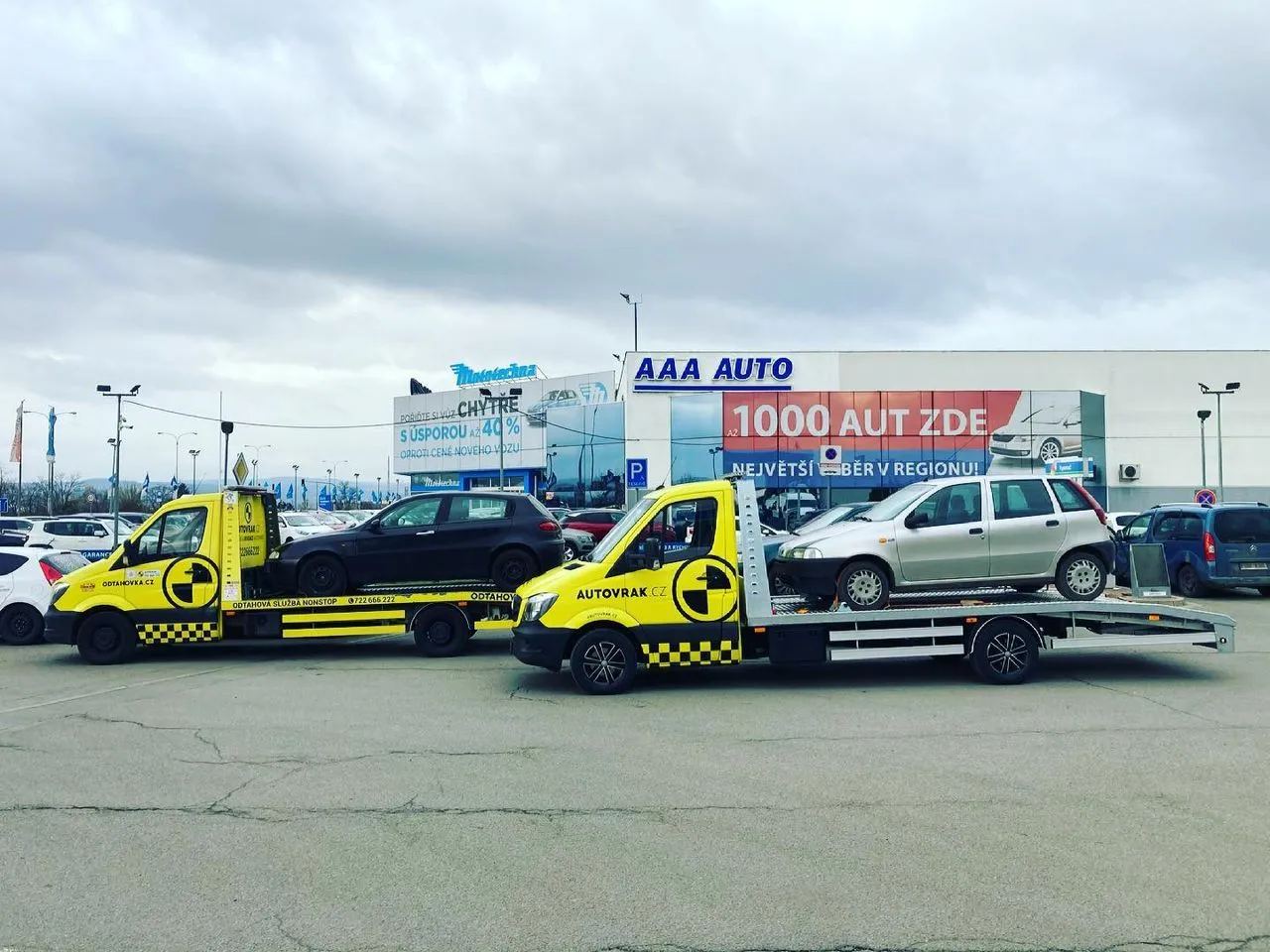 Vůz Autovrak.cz s přívěsem před stěnou vyřazených vozidel