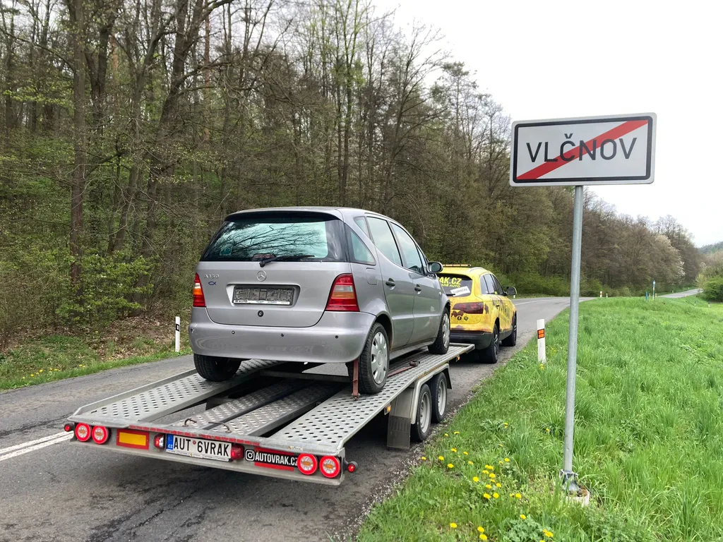 Naložený osobní vůz na přívěsu při odvozu z Vlčnova